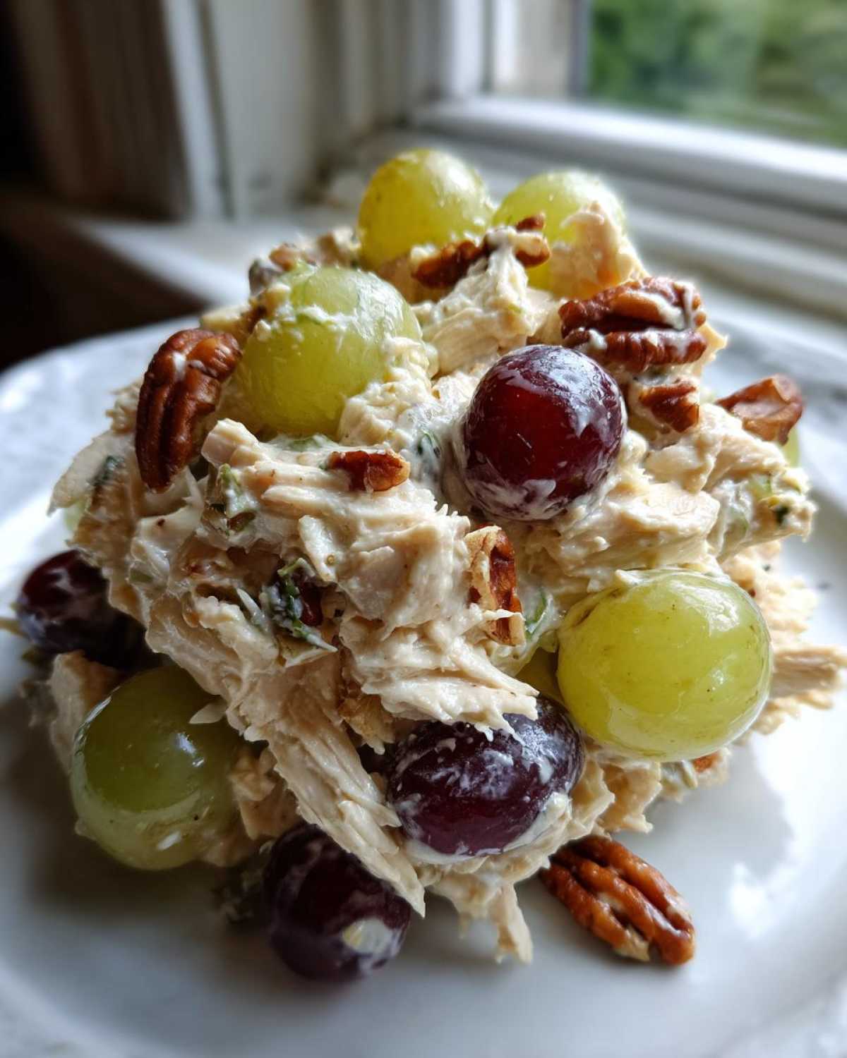 A mound of creamy Honey Mustard Chicken Salad with Grapes and pecans served on a white plate.