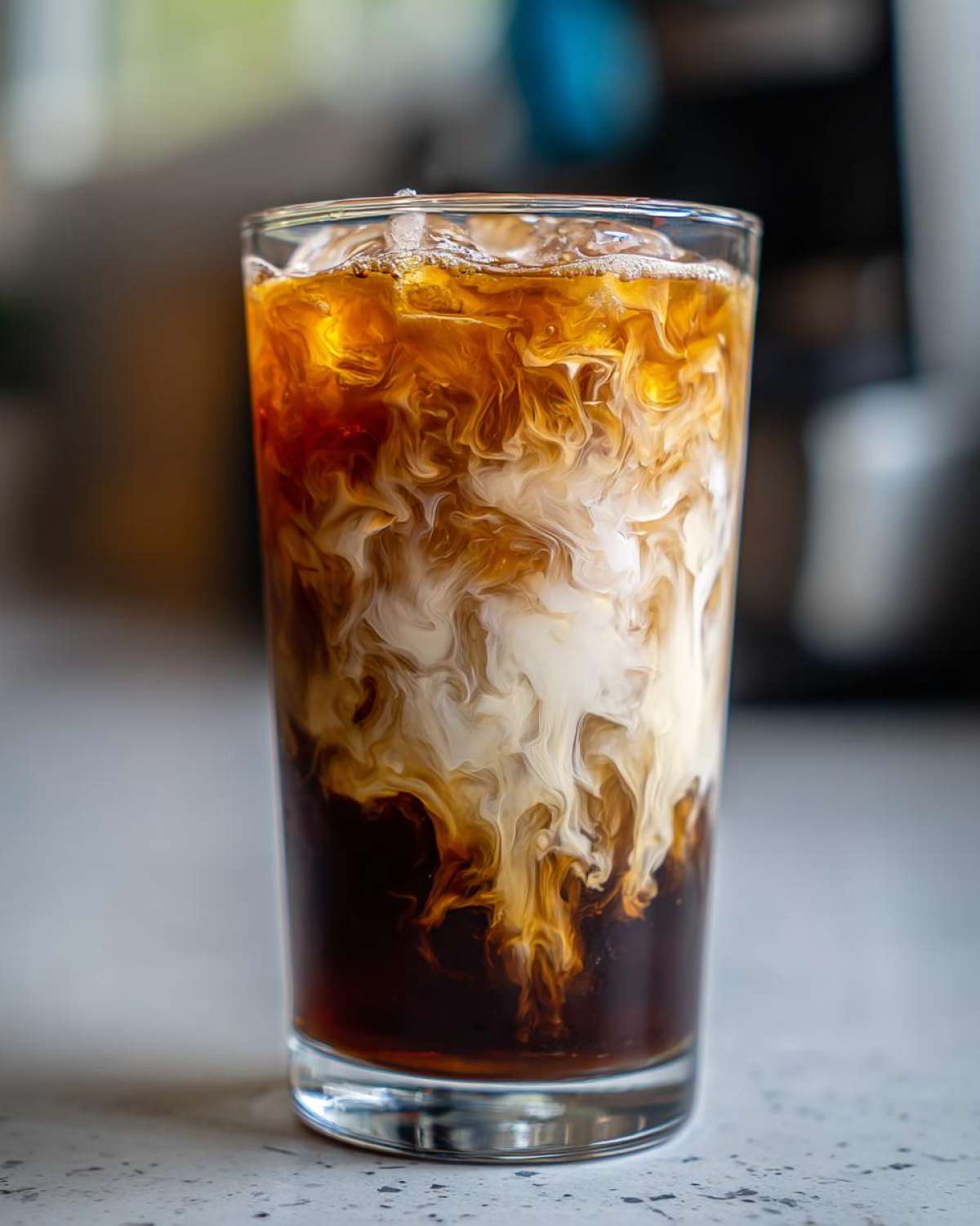 Close-up of an Iced Honey Almond Milk Latte showing the beautiful swirl pattern as the almond milk mixes with dark coffee.