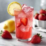 A tall glass filled with vibrant red Iced Strawberry Lemon Tea, ice, and strawberry slices, garnished with a lemon wheel.