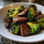 Close-up of tender beef pieces and bright green broccoli florets coated in a rich brown sauce for Instant Pot Beef and Broccoli.