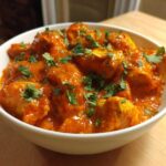 A close-up of rich, orange-red Instant Pot Butter Chicken pieces garnished with fresh cilantro.