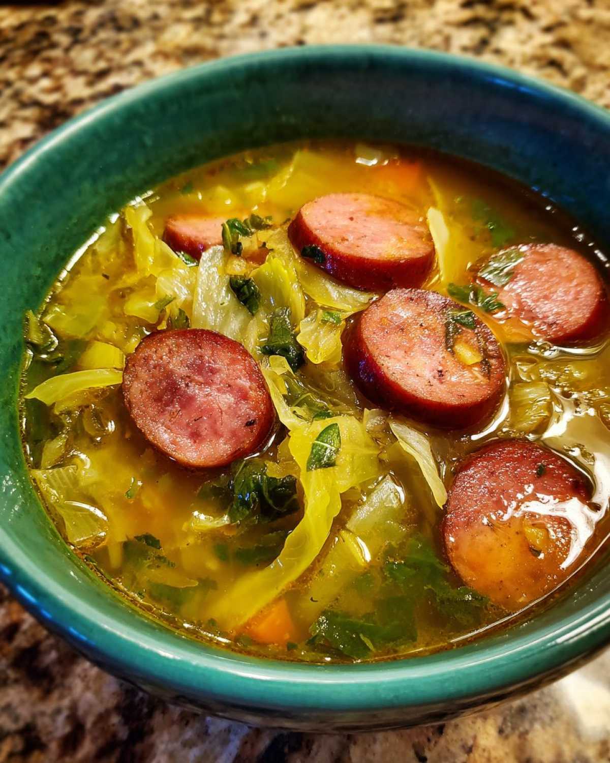 Close-up of a bowl of Instant Pot Cabbage and Sausage Soup with sliced sausage and cabbage.
