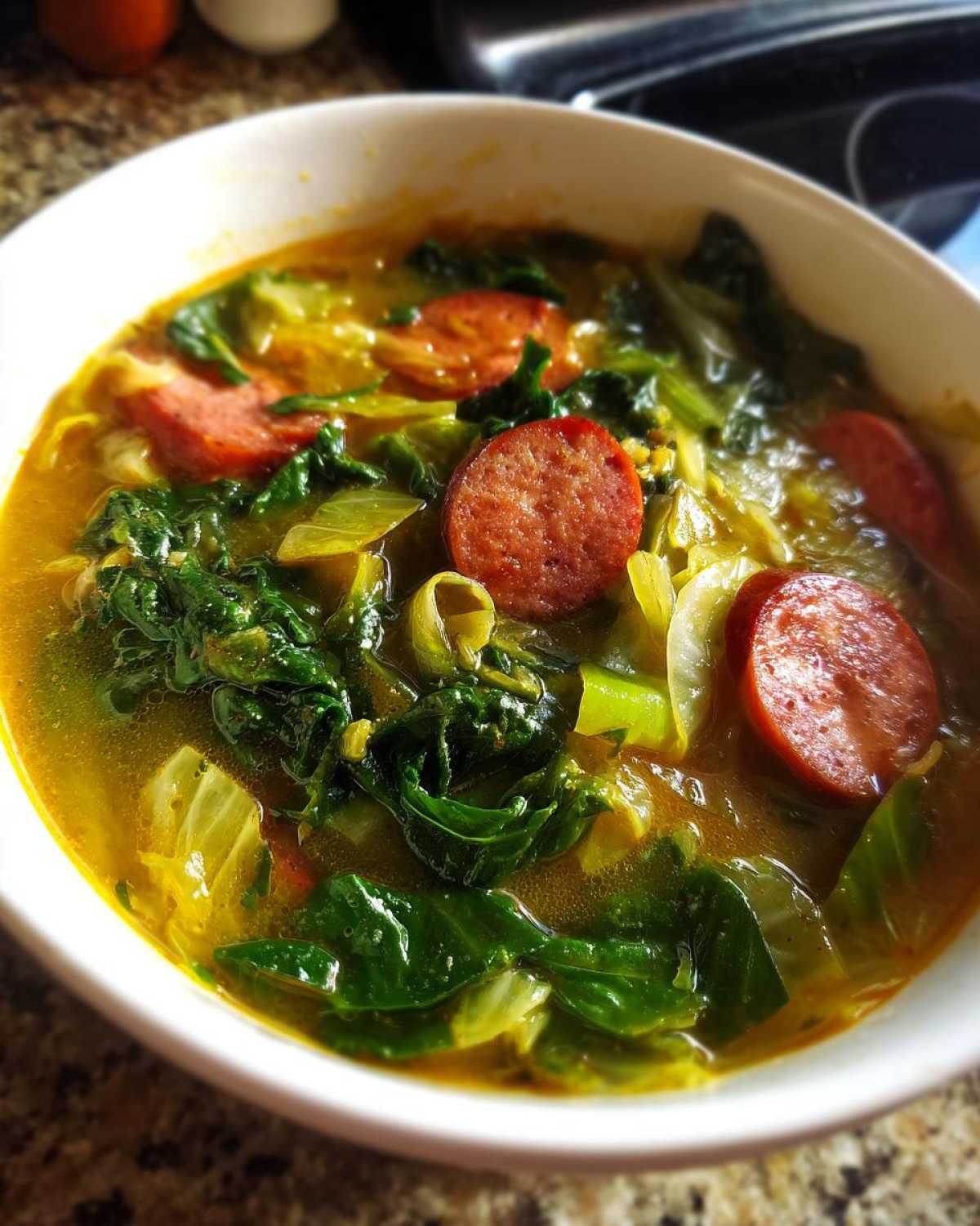 Close-up of a bowl of Instant Pot Cabbage and Sausage Soup featuring sliced sausage and vibrant green cabbage.
