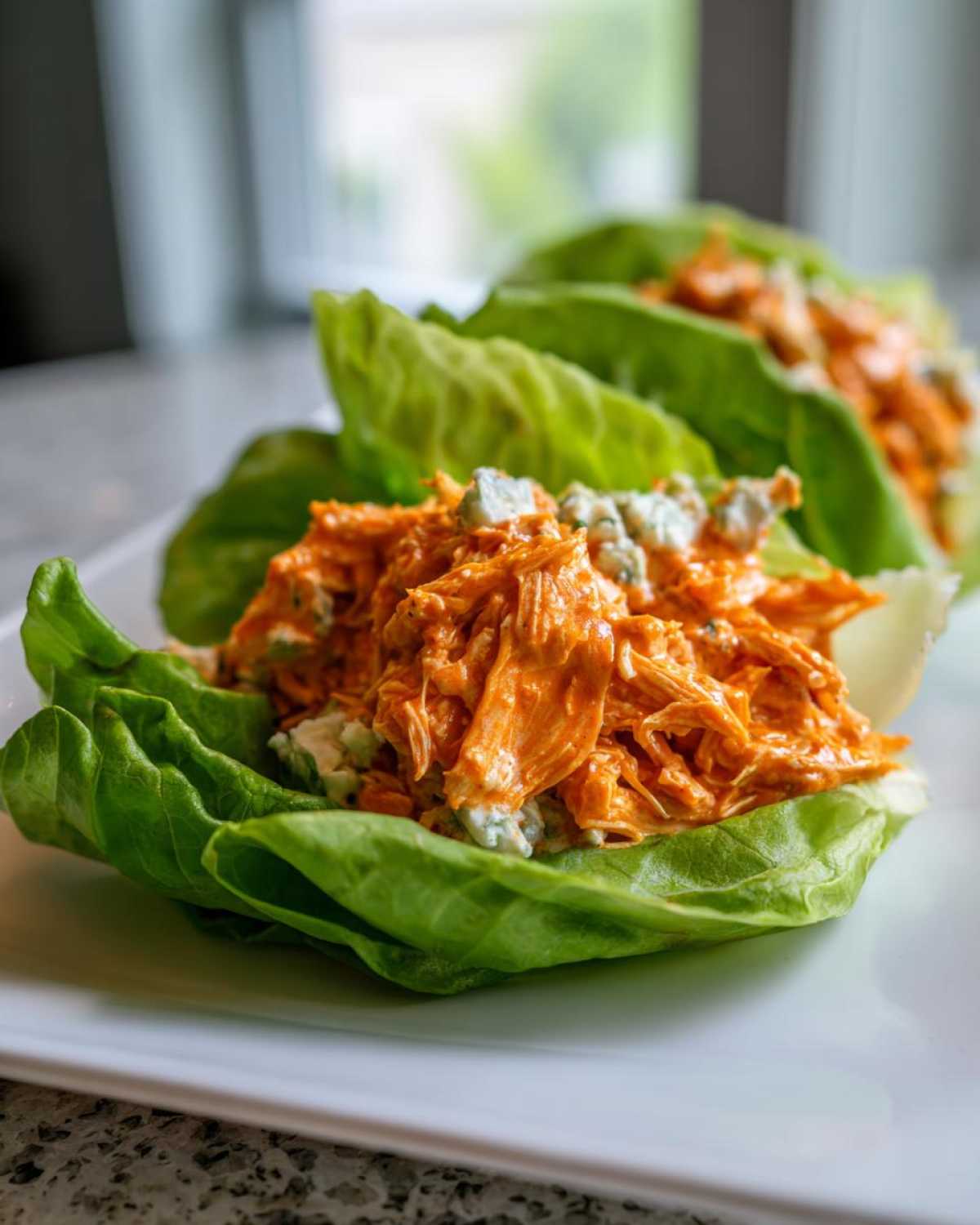 Close-up of Keto Buffalo Chicken Lettuce Wraps filled with orange buffalo chicken salad and blue cheese crumbles.
