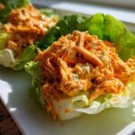 Close-up of shredded chicken mixed with orange buffalo sauce and blue cheese in crisp lettuce cups, showcasing Keto Buffalo Chicken Lettuce Wraps.