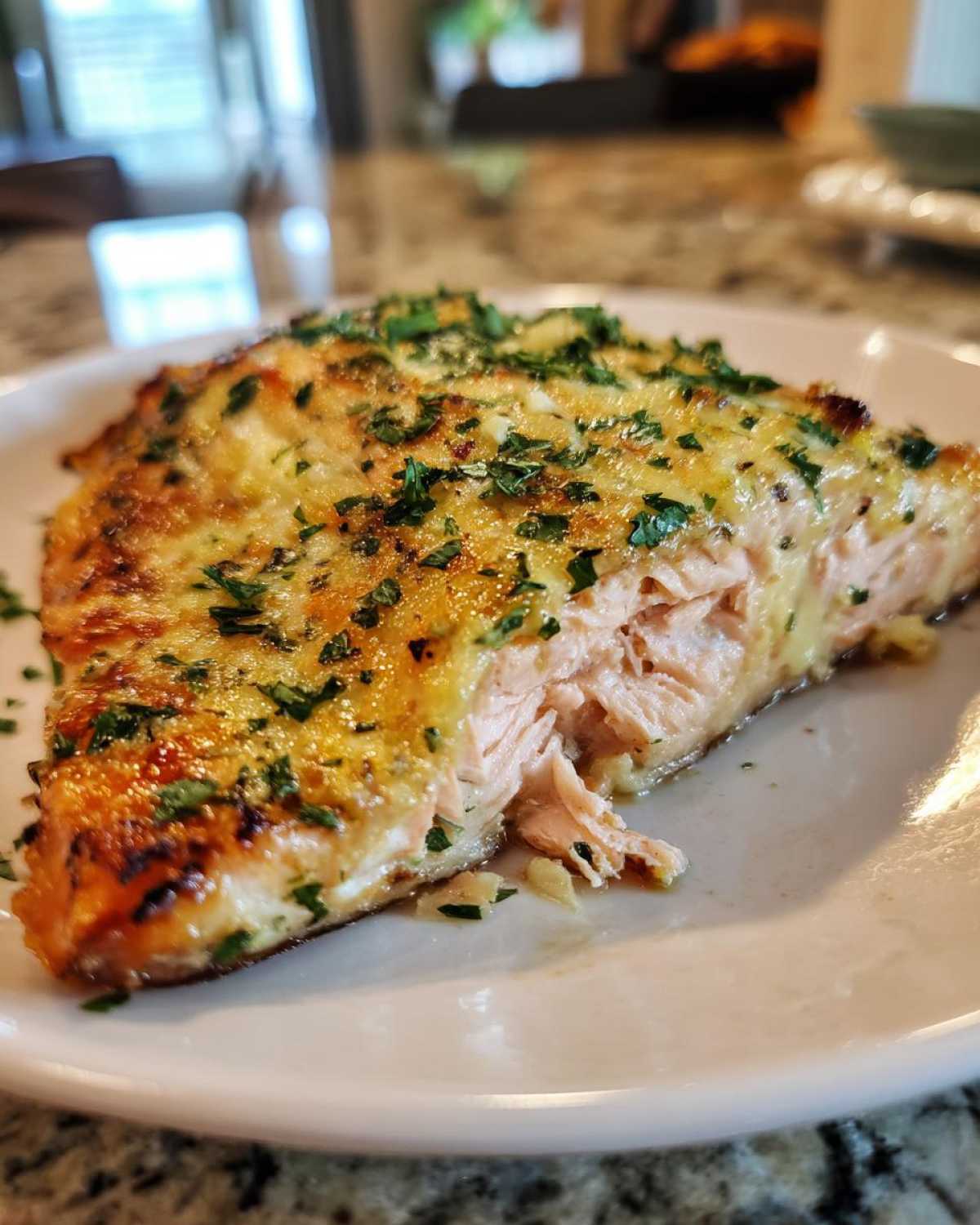 Close-up of a flaky, baked salmon fillet topped with melted butter sauce and fresh parsley, ready to eat Keto Garlic Butter Salmon.