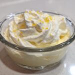 Close-up of single serving Keto Lemon Cheesecake Mousse topped with whipped cream and lemon zest.