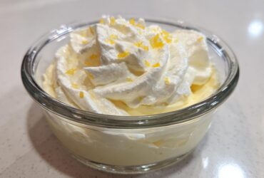 Close-up of single serving Keto Lemon Cheesecake Mousse topped with whipped cream and lemon zest.