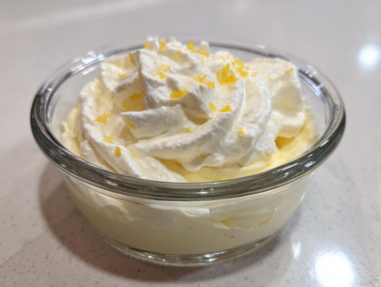 Close-up of single serving Keto Lemon Cheesecake Mousse topped with whipped cream and lemon zest.