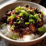 A close-up of Korean Ground Beef Bulgogi Bowls featuring savory ground beef over white rice, garnished with sliced green onions and sesame seeds.