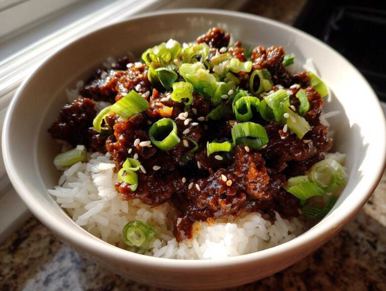 A close-up of Korean Ground Beef Bulgogi Bowls featuring savory ground beef over white rice, garnished with sliced green onions and sesame seeds.