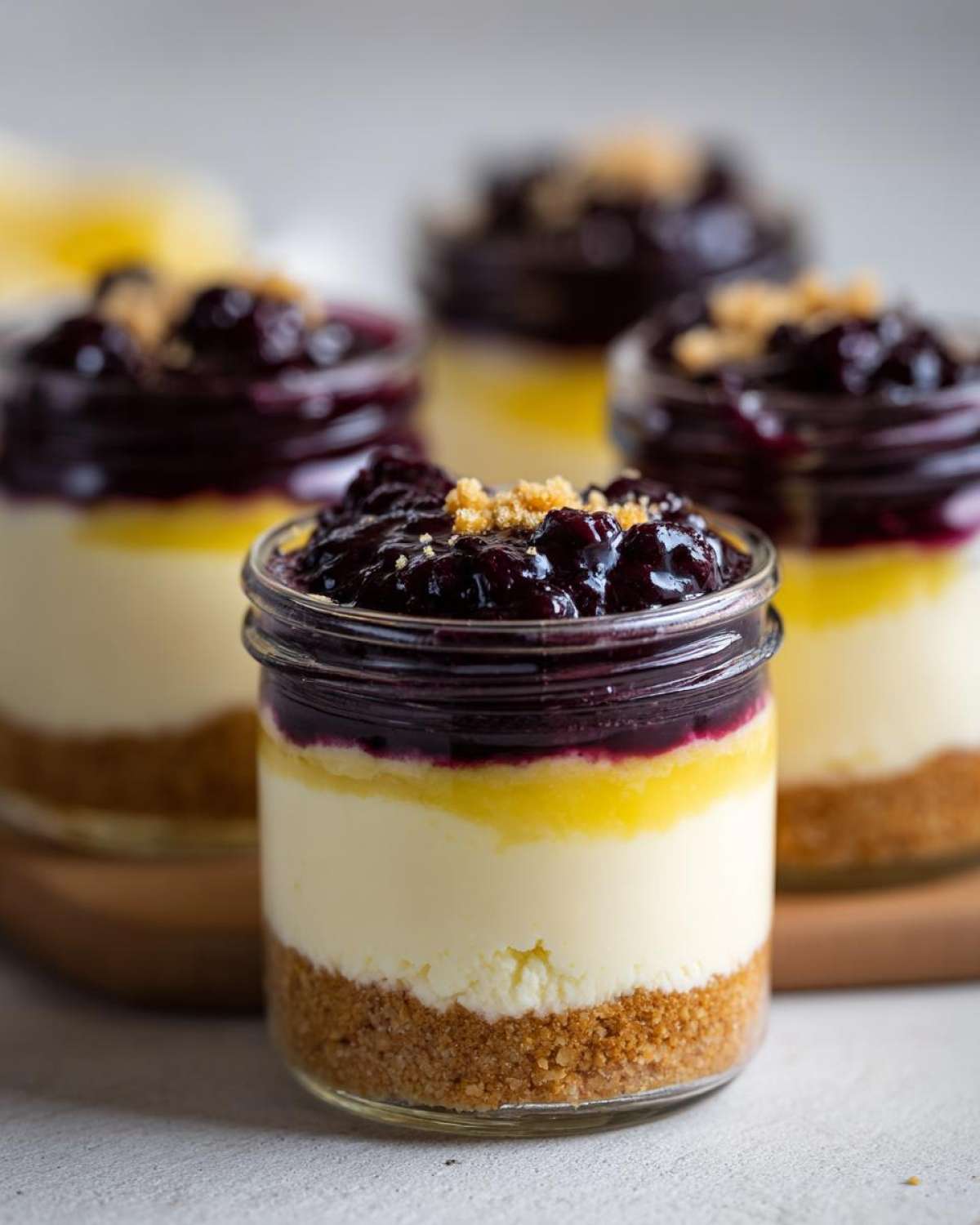 Close-up of layered Lemon Blueberry Cheesecake Jars with graham cracker crust and blueberry topping.