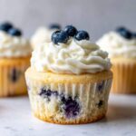 Close-up of a Lemon Blueberry Cupcake topped with swirled cream cheese frosting and three fresh blueberries.