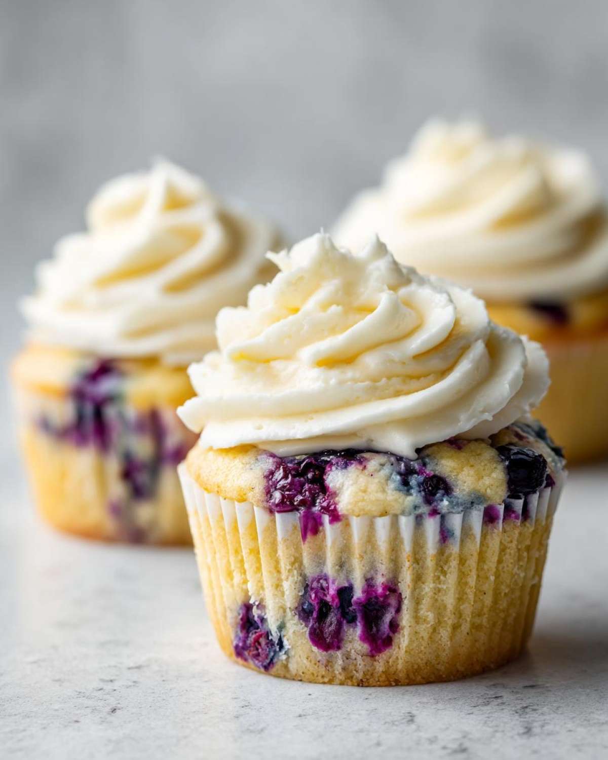 Close-up of a Lemon Blueberry Cupcake topped with swirled cream cheese frosting.