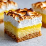 A perfect square of Lemon Meringue Pie Bars showing the crust, lemon filling, and toasted meringue topping.