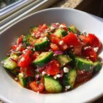 Close-up of a fresh Mediterranean Cucumber Tomato Salad with feta cheese and red onion in a white bowl.