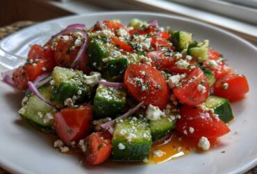 A close-up of fresh Mediterranean Cucumber Tomato Salad featuring chopped tomatoes, cucumbers, red onion, and crumbled feta cheese.