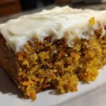 Close-up of a very moist carrot cake with cream cheese frosting showing the texture.