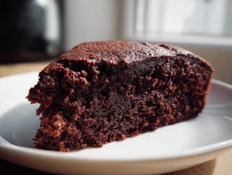 Close-up of a moist, dark slice of Gluten-Free Chocolate Cake on a white plate.