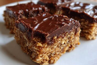 Close-up of thick, layered No-Bake Chocolate Peanut Butter Oat Bars with a shiny chocolate topping.