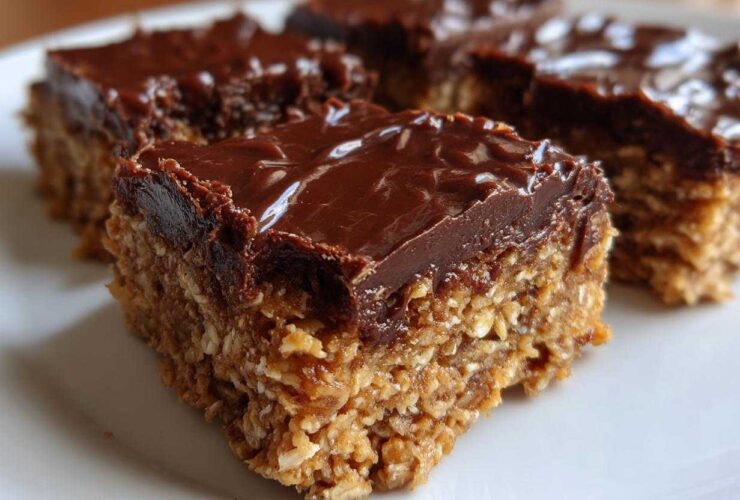 Close-up of thick, layered No-Bake Chocolate Peanut Butter Oat Bars with a shiny chocolate topping.