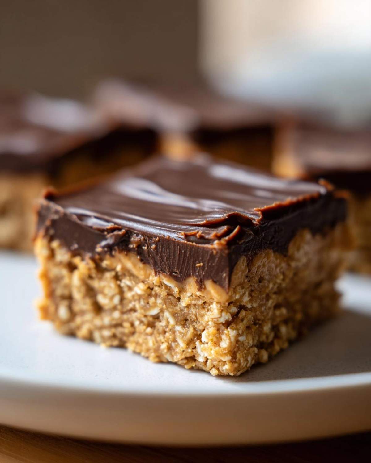 A close-up shot of a single square of No-Bake Chocolate Peanut Butter Oat Bars on a white plate.