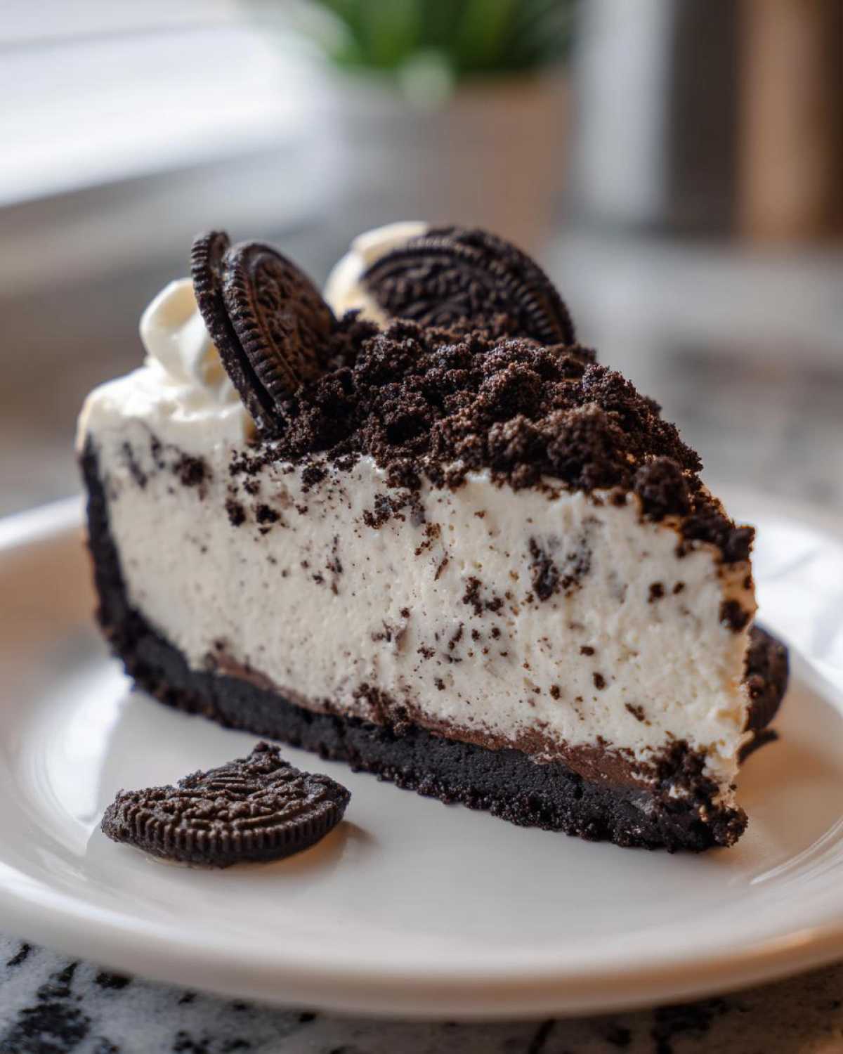 A decadent slice of No-Bake Oreo Cheesecake topped with whipped cream and crushed cookies.