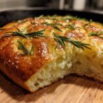 Close-up of golden No-Knead Skillet Focaccia with rosemary sprigs and coarse salt.