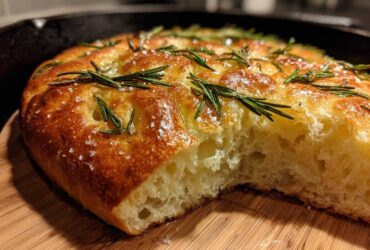 Close-up of golden No-Knead Skillet Focaccia with rosemary sprigs and coarse salt.