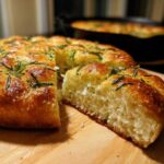 A slice of fluffy No-Knead Skillet Focaccia with Rosemary showing its airy crumb, topped with herbs and sea salt.