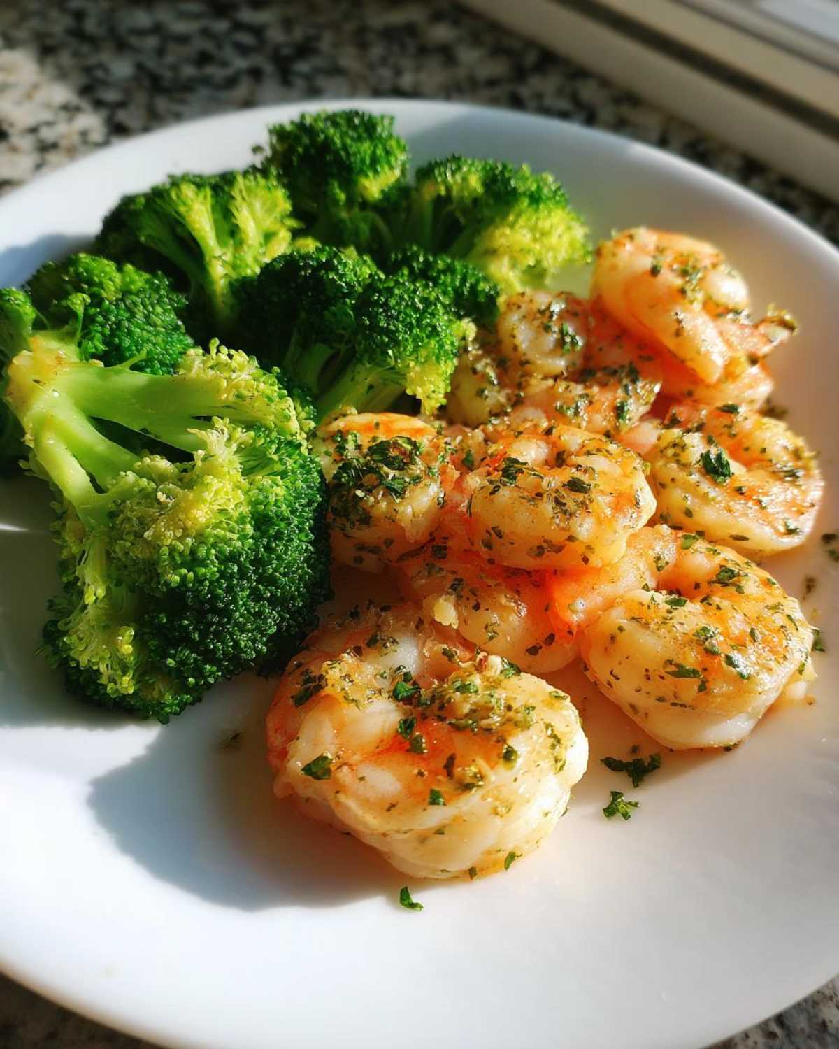 Close-up of cooked shrimp seasoned with herbs next to bright green broccoli florets, representing Sheet Pan Garlic Butter Shrimp and Broccoli.