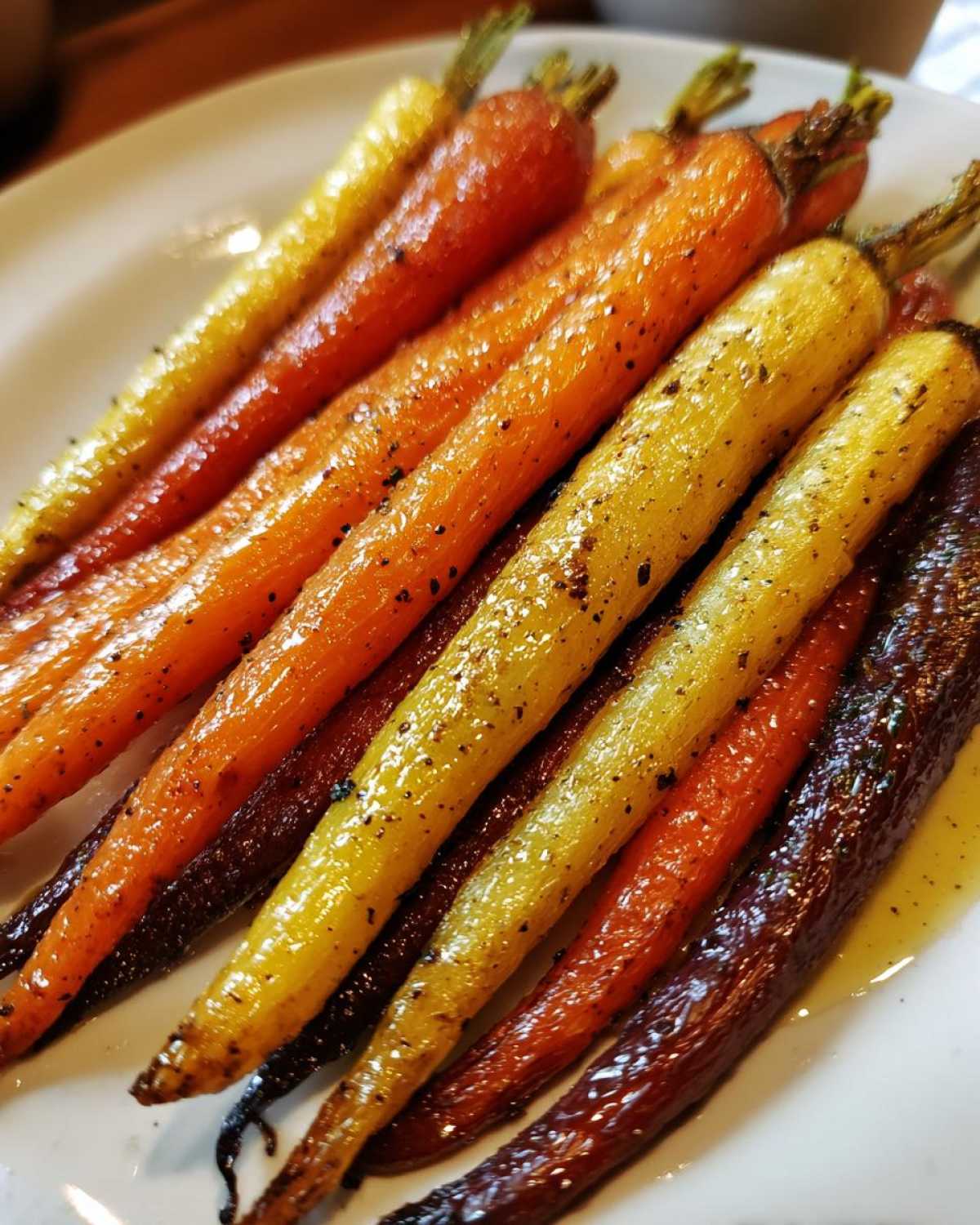 Close-up of glossy Sheet Pan Roasted Rainbow Carrots with Honey on a white plate, showing yellow, orange, and purple varieties.