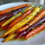 Close-up of glossy Sheet Pan Roasted Rainbow Carrots with Honey, garnished with fresh thyme sprigs.