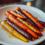 Close-up of glazed Sheet Pan Roasted Rainbow Carrots with Honey on a white plate, sprinkled with herbs.