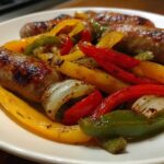A close-up view of perfectly cooked Sheet Pan Sausage and Peppers, featuring browned sausages mixed with colorful roasted bell peppers and onions.