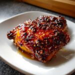 Close-up of two Spicy Honey Garlic Air Fryer Chicken Thighs covered in a dark, sticky, caramelized glaze.