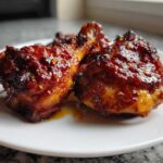 Close-up of two glazed Spicy Honey Garlic Air Fryer Chicken Thighs on a white plate.