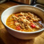 Close-up of a white bowl filled with Spicy Turkey White Bean Chili, showing ground turkey, white beans, and red peppers in a rich broth.