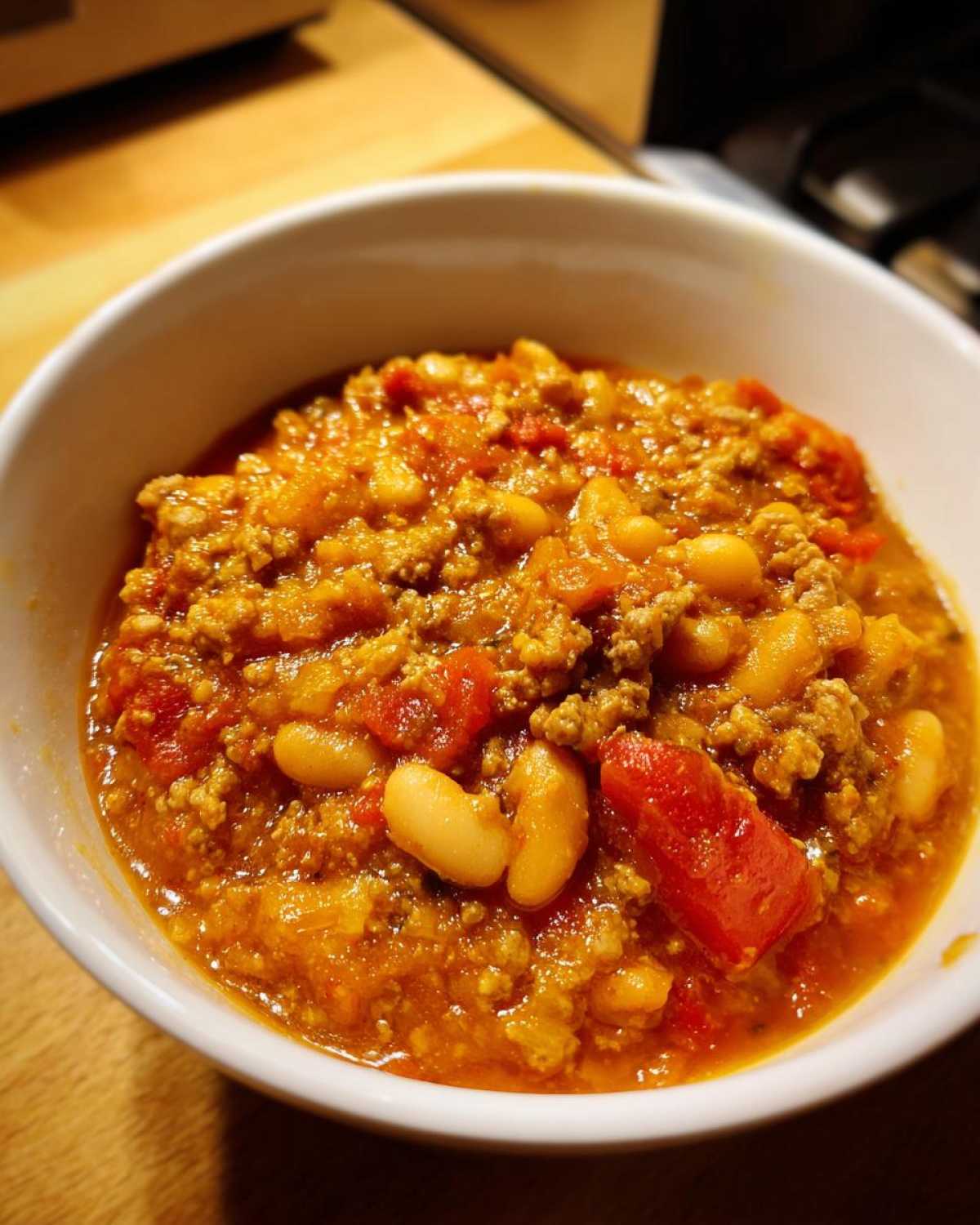 A close-up view of a hearty bowl of Spicy Turkey White Bean Chili, showing ground turkey, white beans, and chunks of tomato in a rich sauce.