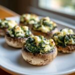 Close-up of baked Spinach and Feta Stuffed Mushrooms served on a white plate.