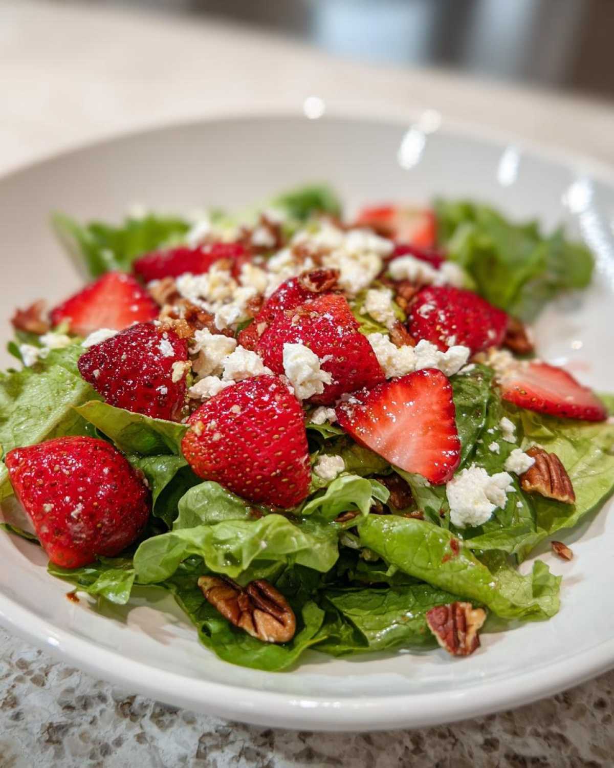 Close-up of a vibrant Spring Mix Salad with Strawberries and Goat Cheese, topped with pecans.