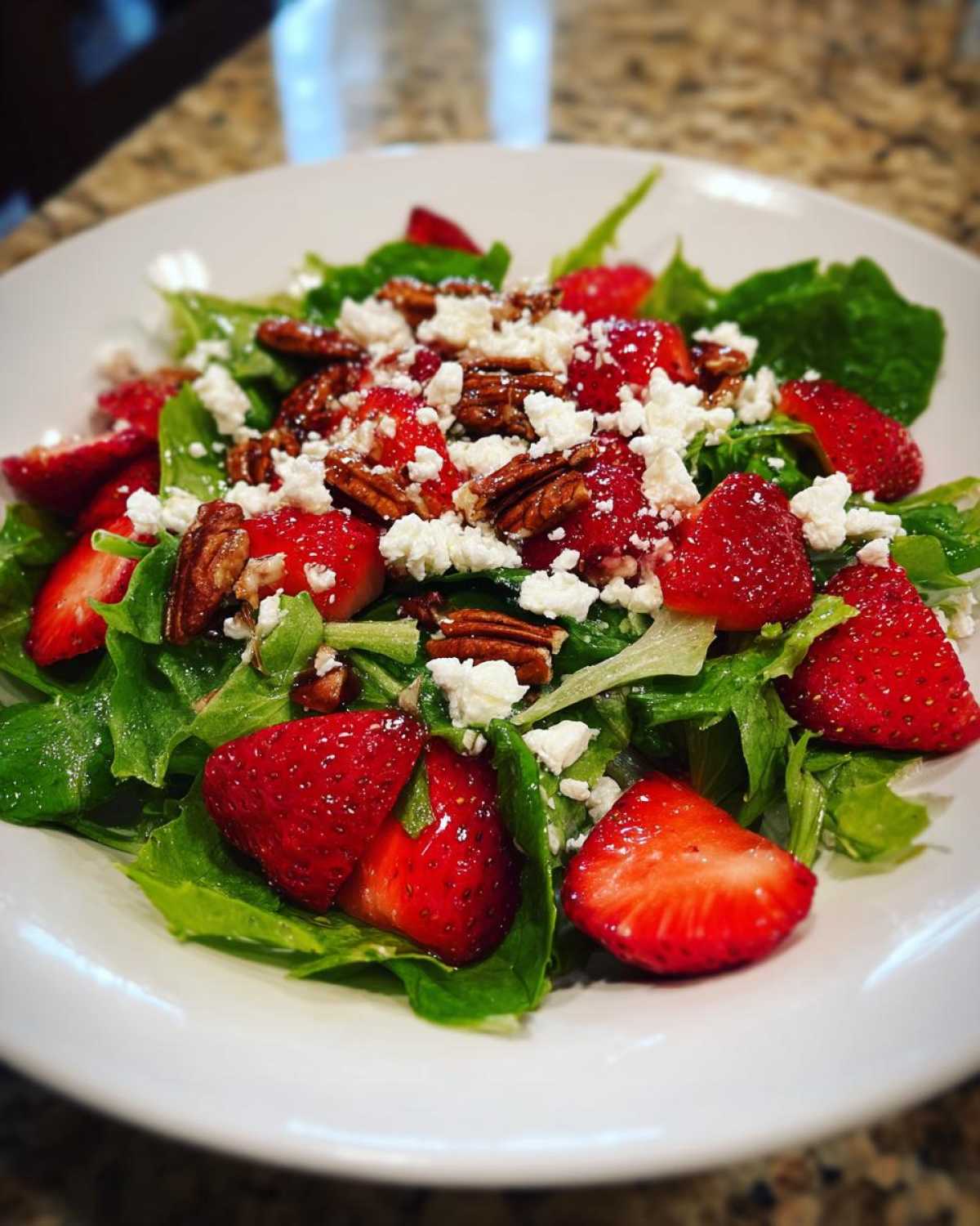 Close-up of a vibrant Spring Mix Salad with Strawberries and Goat Cheese, topped with pecans.
