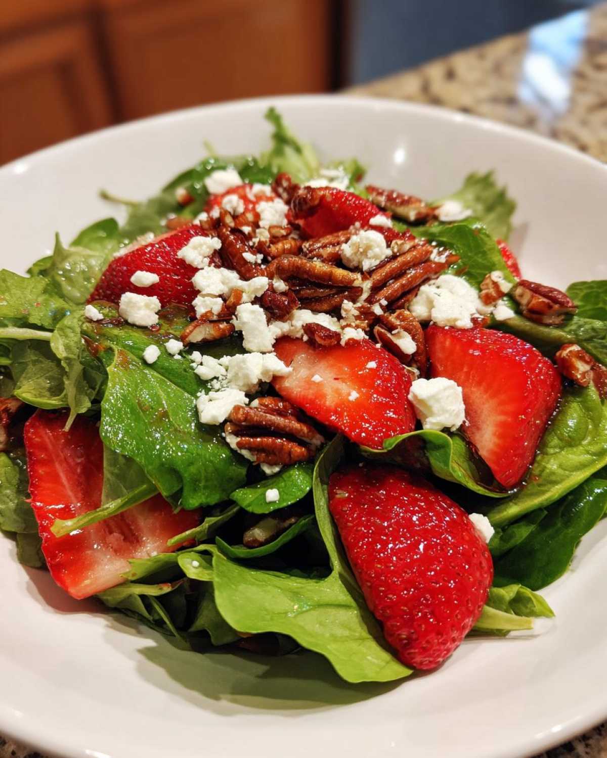 Close-up of a vibrant Spring Mix Salad with Strawberries and Goat Cheese, topped with pecans.