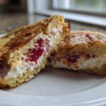 Close-up of Strawberry Cream Cheese Stuffed French Toast cut in half, showing creamy filling and strawberries.