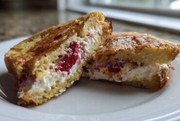 Close-up of Strawberry Cream Cheese Stuffed French Toast cut in half, showing creamy filling and strawberries.