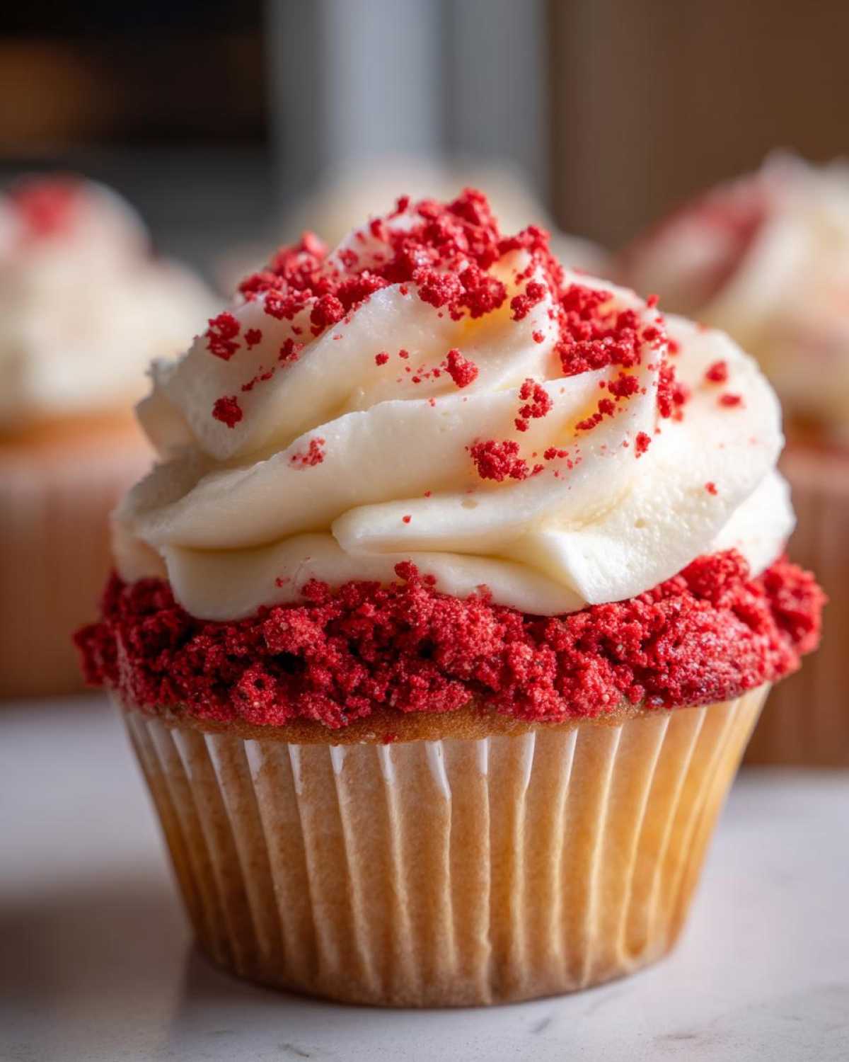 A close-up of a single Strawberry Crunch Cupcakes topped with white cream cheese frosting and bright red strawberry crunch coating.