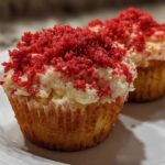 Two delicious Strawberry Crunch Cupcakes topped with white frosting and bright red crunchy crumbs.