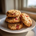 A stack of golden brown Strawberry Oatmeal Breakfast Cookies studded with visible pieces of bright red strawberry.