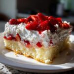 A delicious slice of Strawberry Shortcake Sheet Cake topped with fresh strawberries and whipped cream on a white plate.