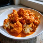 Close-up of bright orange Vegan Cauliflower Tikka Masala featuring tender cauliflower florets coated in rich, creamy sauce.